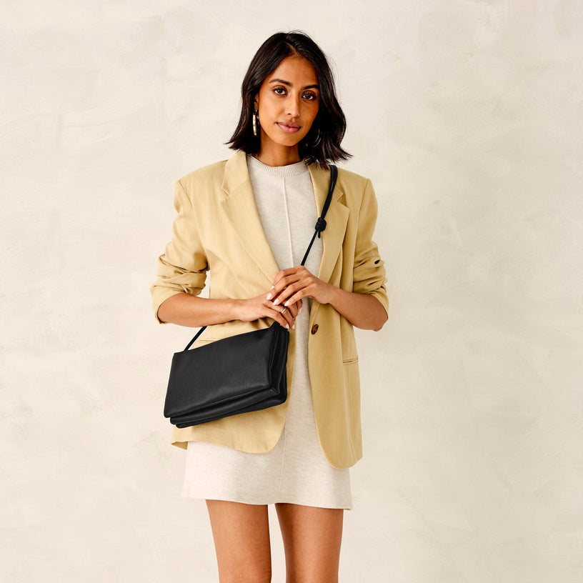 Model wearing black leather crossbody bag over work attire