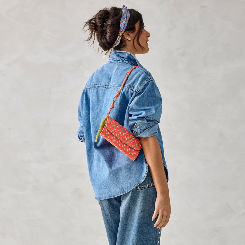 Model wearing demin with bright pink and green wallet crossbody slung over shoulder