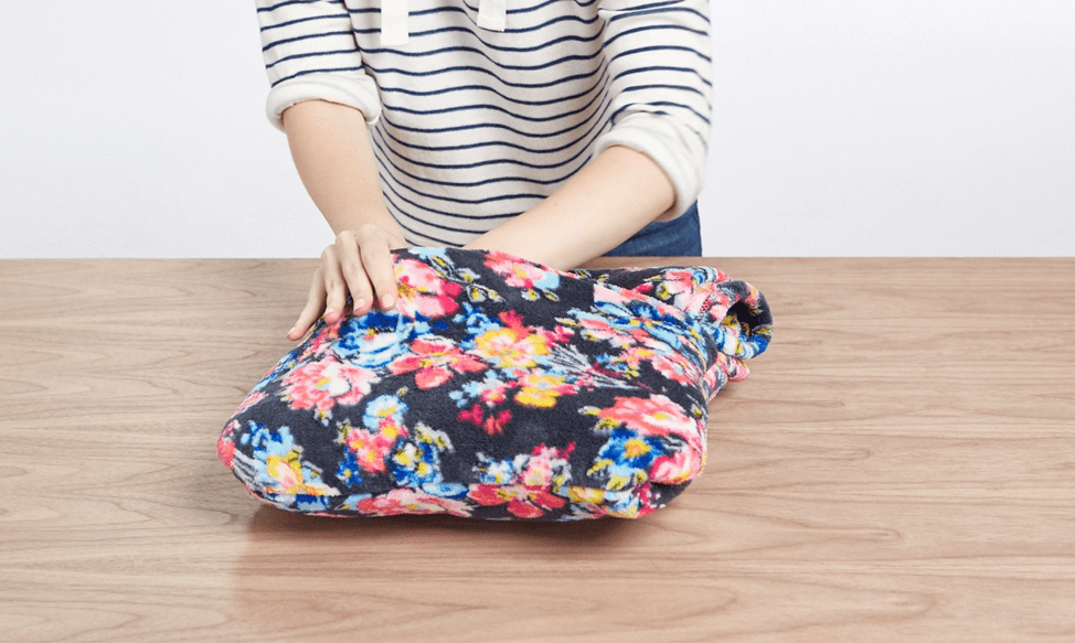 Person tucking a fleece blanket into the built-in pouch